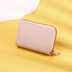 Detail of a pink women's mini wallet showing its smooth texture and gold zipper