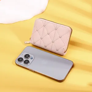 Detail of a pink quilted heart wallet showing compact size compared to a phone