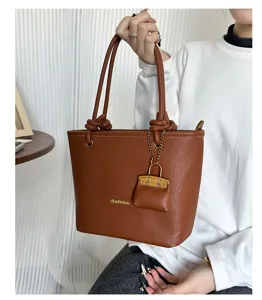 Detail view of brown lychee grain tote bag with decorative knot handles and charm