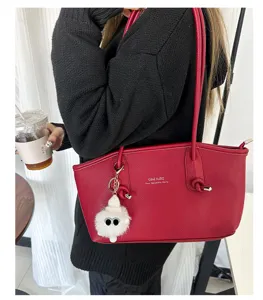 Detail view of red textured PU leather tote bag featuring a cute white fluffy bag charm