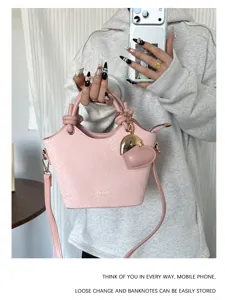 Primo piano del secchiello in pelle PU rosa con ciondolo a cuore e trama serpente