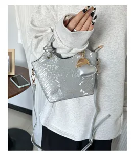 Elegante borsa a secchiello in PU argento pitonato con ciondolo a cuore in scena