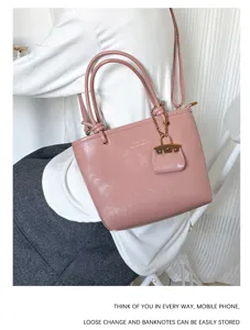 A stylish dusty pink retro tote bag shown in a lifestyle shoulder carry view with pouch charm