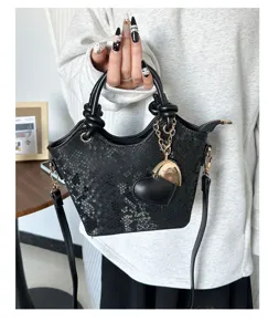 Dettaglio dell'elegante borsa a mano nera con motivo a serpente e ciondolo a cuore