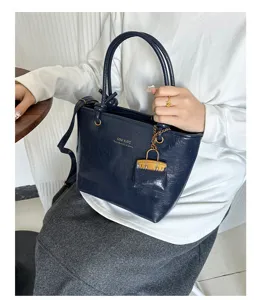 Close-up of a vintage navy blue textured tote bag held by a model in a casual setting.