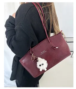Crocodile embossed burgundy tote bag worn by a model in a stylish commuter look