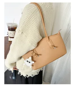 Detail of tan PU leather underarm bag worn over a knit sweater for stylish commuting