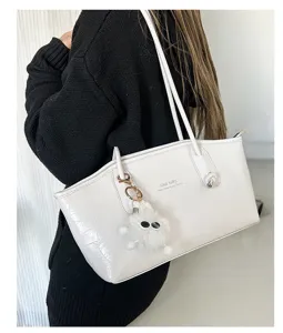 Detail of the white crocodile-patterned tote bag with a white fur charm accessory