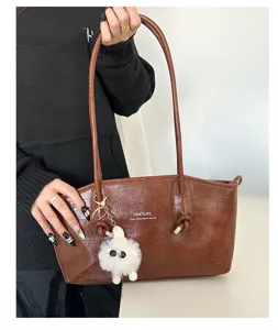 Detailed view of brown crocodile pattern tote bag featuring a cute white fur ball charm