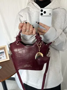 Piccola borsa a secchiello bordeaux motivo coccodrillo con ciondolo a cuore