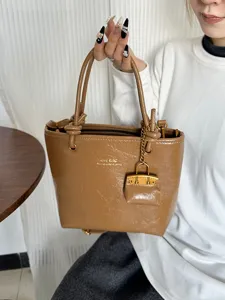 Retro brown glossy tote bag for women featuring knot handles and a decorative charm