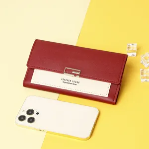 Close-up detail of a stylish red and cream trifold long wallet next to a smartphone