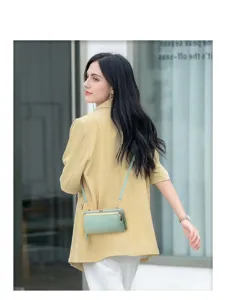 Model trägt eine minzgrüne Umhängetasche mit einem stylischen gelben Blazer
