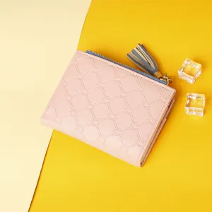 Close-up of pink women's compact wallet with tassel and sunburst embossed pattern