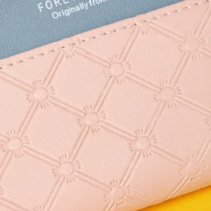 Macro view of the pink embossed leather texture and fine stitching on a bicolor wallet.