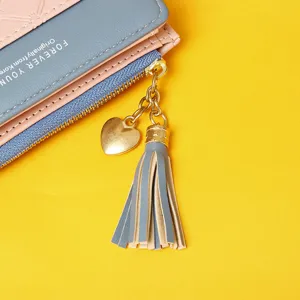 Close-up of women's color-blocking wallet with gold heart charm and leather tassel detail