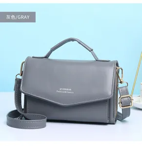 Vooraanzicht van een grijze multifunctionele crossbody telefoontas met stijlvolle gouden hardware
