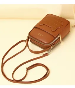Detailed studio shot of a brown mini crossbody bag with cartoon pocket and dual zippers