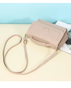 Close-up detail of the textured nude handbag showing the top handle and gold accents