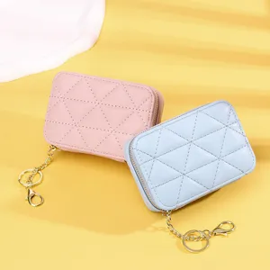 Zwei Mini-Münztaschen aus gestepptem Leder mit goldenen Schlüsselanhängern in Pink und Blau.