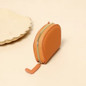 Detailed side view of orange lychee texture leather mini coin purse with gold zipper