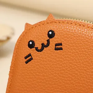 Detail view of the cute embroidered cat face and textured leather of the wallet