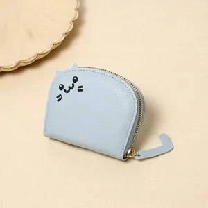 Detailed macro shot of light blue cat-shaped coin purse with embroidered face and tail zipper.