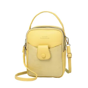 Stylish yellow mini crossbody phone bag with crocodile stone pattern and top handle.
