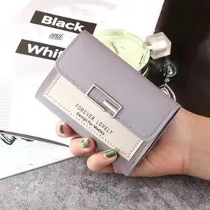 Nahaufnahme einer lila dreifaltigen Geldbörse mit 'Forever Lovely'-Text und Metallschnalle