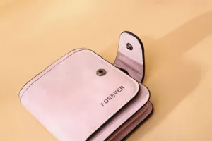 Macro detail view of pink matte PU leather wallet with 'FOREVER' print and snap button.