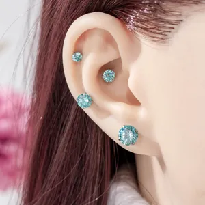Detailed view of four round-cut aquamarine gemstone cartilage studs worn on a model's ear