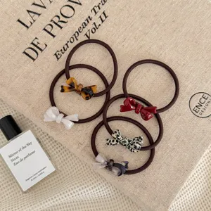 Set of five elastic hair ties with colorful resin bow accents on textured background