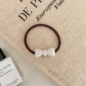 Detailed macro view of a brown elastic hair tie with a white bow ornament