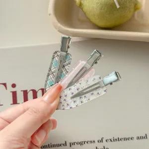 Detail of floral and plaid patterned no-bend alligator hair clips held in hand