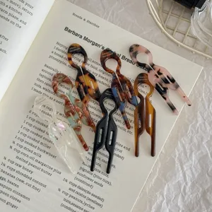 Detailed view of multiple acetate fish-shaped U-hairpins on an open book page