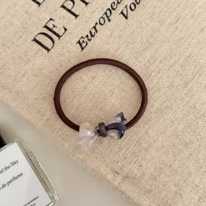 Close-up of a brown elastic hair tie with a stylish marbled purple resin bow charm detail