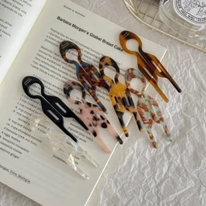 Variety of acetate U-shaped hair pins with marble and tortoiseshell patterns on book.
