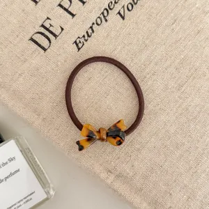 Detailed close-up of a tortoiseshell bow hair elastic resting on a rustic linen background