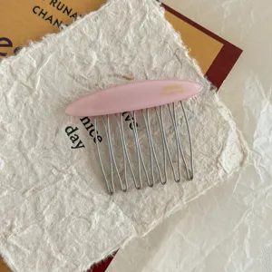 Detail view of pink acetate hair comb with metal teeth and France Handmade engraving