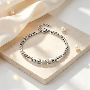 Detail shot of a silver stainless steel watch strap style chain bracelet on marble slab
