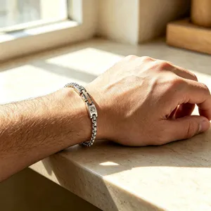 Close-up of a two-tone stainless steel watchband link and box chain bracelet on a male wrist.