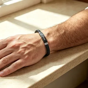 Dettaglio di un braccialetto in pelle intrecciata da uomo con croce nera.