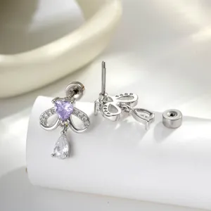 Vue rapprochée de boucles d'oreilles nœud avec zircon cœur violet et goutte d'eau