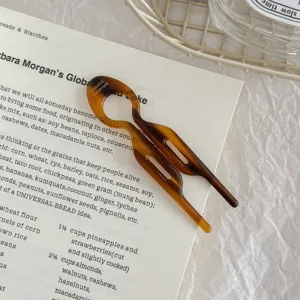 Close-up view of a tortoise shell acetate fish hair pin resting on an open book page