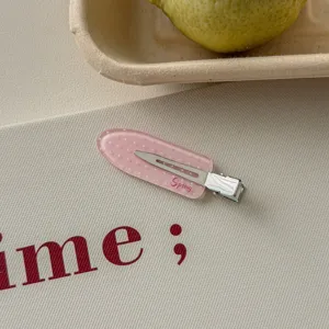 Macro detail of a pink polka dot duckbill hair clip with decorative Spring text print