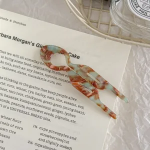 Close-up detail view of acetate U-shaped hair fork with mint green and brown marble pattern