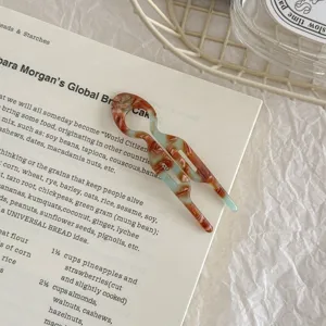 Close-up detail of acetate U-shaped hair fork with tortoiseshell pattern on book