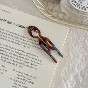 Detailed view of a tortoiseshell acetate small fish-shaped hair fork on a book