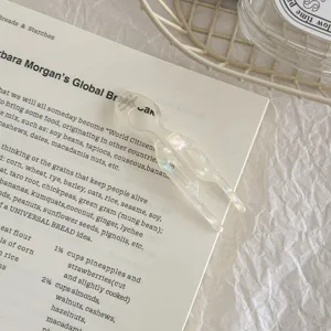 Close-up detail of a pearlescent acetate fish-shaped U-pin hair fork on a printed book