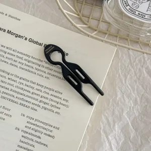 Detailed close-up of a minimalist black fish-shaped acetate U-shaped hairpin for buns